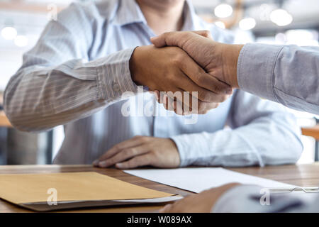 Finishing up a meeting, handshake of two happy business people after contract agreement to become a partner, collaborative teamwork. Stock Photo