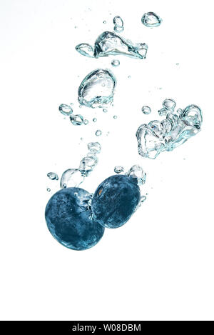 Two blueberry’s splashing into crystal clear water with air bubbles Stock Photo