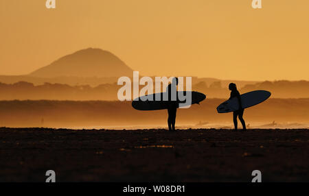 Surfers on Belhaven beach near Dunbar in the Scottish Borders after the sun set. Stock Photo