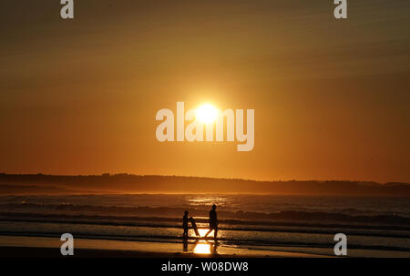 Surfers on Belhaven beach near Dunbar in the Scottish Borders after the sun set. Stock Photo