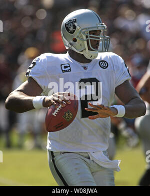 Oakland Raiders QB JaMarcus Russell (2) throws a pass with San Diego  Chargers Larry English holding his legs at the Oakland Coliseum in Oakland,  California on September 14, 2009. The Chargers defeated