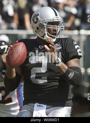 Oakland Raiders QB JaMarcus Russell (2) throws a pass with San Diego  Chargers Larry English holding his legs at the Oakland Coliseum in Oakland,  California on September 14, 2009. The Chargers defeated