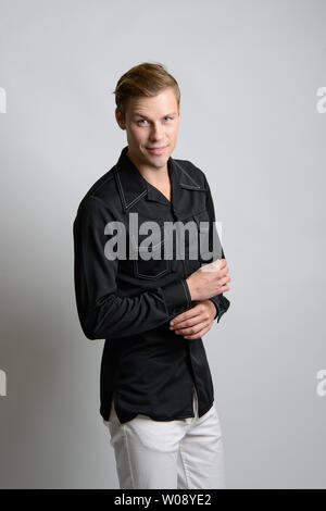 A Brown hair Caucasian male model poses in vintage clothing outfit, he wears a black shirt, a men's vintage fashion editorial. Stock Photo