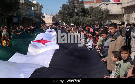 Demonstrators hold a large Syrian opposition flag during a protest against Syria's President Bashar al-Assad in Kafranbel near Idlib, in Syria, February 24,2012. Syrian troops shelled the rebel stronghold in Homs for the 22nd straight day, after a pause allowed relief workers to evacuate some civilians, monitors said. UPI. Stock Photo