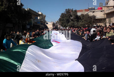 Demonstrators hold a large Syrian opposition flag during a protest against Syria's President Bashar al-Assad in Kafranbel near Idlib, Syria, February 24, 2012. Syrian troops shelled the rebel stronghold in Homs for the 22nd straight day, after a pause allowed relief workers to evacuate some civilians, monitors said. UPI Stock Photo