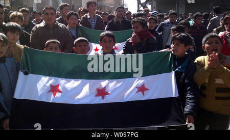 Demonstrators hold  Syrian opposition flag during a protest against Syria's President Bashar al-Assad in Kafranbel near Idlib, in Syria, February 24, 2012. Syrian troops shelled the rebel stronghold in Homs for the 22nd straight day, after a pause allowed relief workers to evacuate some civilians, monitors said.  UPI Stock Photo