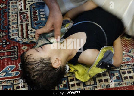 A child, affected by what activists say is nerve gas, breathes through an oxygen mask in Damascus suburbs in Syria, August 21, 2013.  Syrian rebels claim hundreds were killed in a toxic gas attack by pro-government forces, and the Syrian government has denied the claims. The UN is investigating.   UPI/Diaa El Din Stock Photo