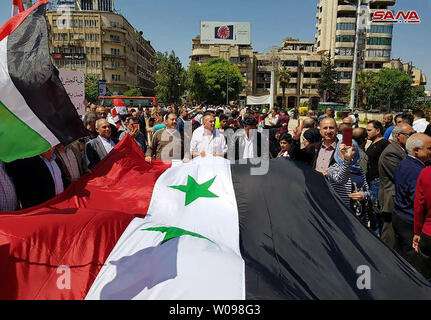 A photo released early on April 14, 2018 on the website of the official Syrian Arab News Agency (SANA) shows an Syrians wave the national flag and wave portraits of President Bashar al-Assad as they gather at Square in Damascus on April 14, 2018, to condemn the strikes carried out by the United States, Britain and France against the Syrian regime. The United States, Britain and France carried out a wave of punitive strikes against Bashar al-Assad's Syrian regime on Saturday in response to alleged chemical weapons attacks. Photo by SANA/UPI Stock Photo