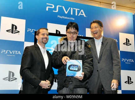 Chairman of Sony Computer Entertainment, Inc., Kazuo Hirai (L) and President and Group CEO of Sony Computer Entertainment Inc., Andrew House (R) pose with the first customer during a launch event for portable video game player 'PlayStation Vita (PS VITA)' at the 'TSUTAYA' Shibuya store in Tokyo, Japan, on December 17, 2011. PS VITA will be released in Europe and U.S. on February 22, 2012.     UPI/Keizo Mori Stock Photo