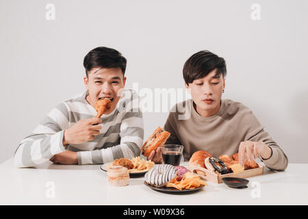 Two friends eating burgers. french fries, having fun and smiling Stock Photo