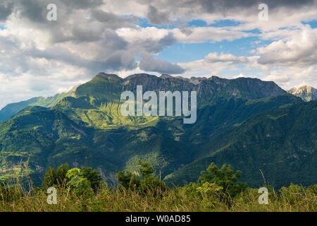 High mountain ridge with sharp rocks and green hills illuminated by sunset sun Stock Photo