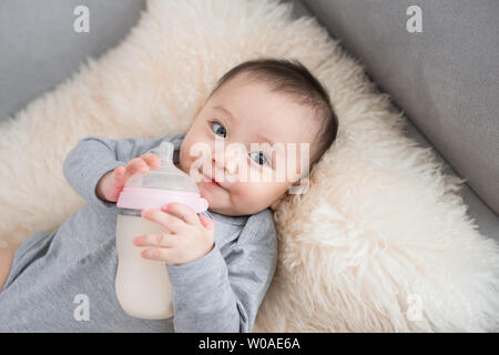 Asian baby infant eating milk from bottle, 9 months after birth Stock Photo