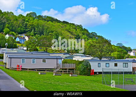 A view of static holiday caravans which overlook Cardigan Bay near Newquay in West Wales.Blue skies & white clouds. Attractive wooded background. Stock Photo