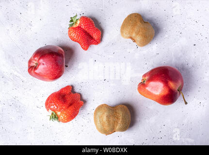 Six ugly fruits and berries laid out in circle on grey concrete background.  Stock Photo