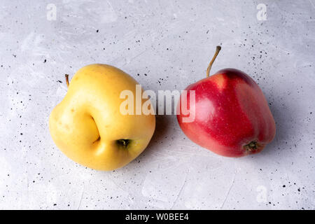 Two ugly red and yellow apples on grey concrete background. Stock Photo