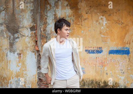 Asian man in casual clothes  standing on old wall background. Stock Photo