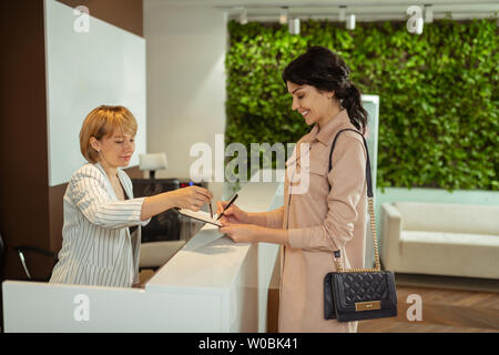 Woman wearing stylish dress writing personal details before visiting doctor Stock Photo