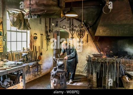 A blacksmith working in his smithy.  A lovely day out viewing the culture, architecture and livelyhoods of old Netherlands Stock Photo