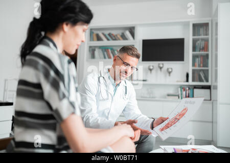 Handsome bearded plastic surgeon consulting woman about face surgery Stock Photo