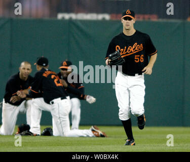 Baltimore Orioles pitcher Brian Burres (56) jogs in from the bullpen as outfielders left fielder Jay Payton (L), right fielder Nick Markakis (21) and center fielder Tike Redman (R) kneel down after pitcher Daniel Cabrera was ejected in the fourth inning after throwing a ball behind Boston Red Sox second baseman Dustin Pedroia at Orioles Park at Camden Yards in Baltimore on September 7, 2007.  (UPI Photo/Mark Goldman) Stock Photo