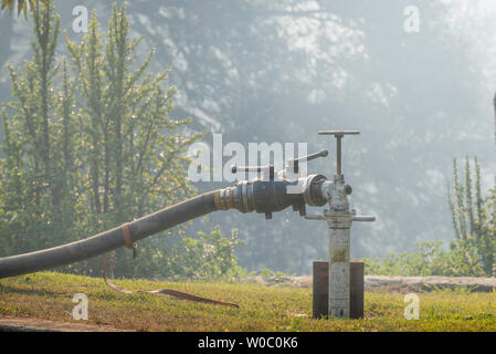 A tap or valve with a fire hose attached and connected to an Australian  style below ground fire hydrant during a hazard reduction burn in Sydney Stock Photo