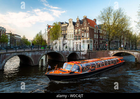 Amsterdam canal cruise ship with Netherlands traditional house in Amsterdam, Netherlands. Stock Photo