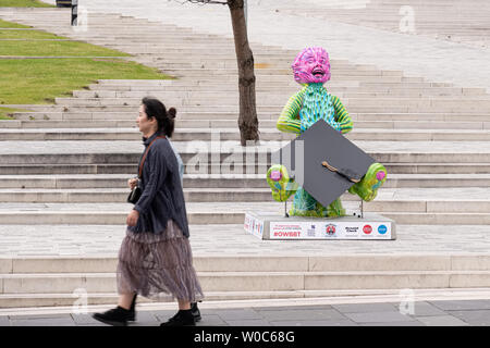 Glasgow, Scotland, UK - June 22, 2019: Two Young ladies walking past the modern statue of ‘Our Wullie’ at the front of the new City of Glasgow College Stock Photo