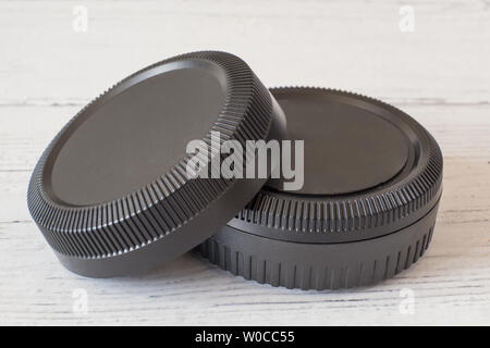 Camera lens caps and body covers on white painted wooden surface Stock Photo