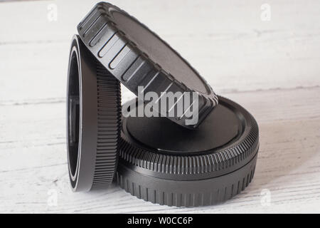 Camera lens caps and body covers on white painted wooden surface Stock Photo
