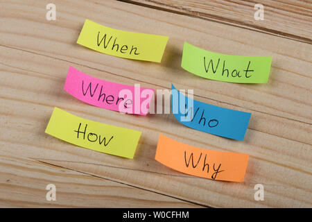 Questions - Why? What? Where? When? Why? How? on colorful stickers on wooden desk Stock Photo