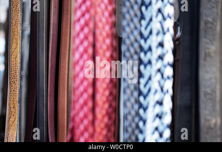 many belts hanging up on a stand out of focus abstract Stock Photo