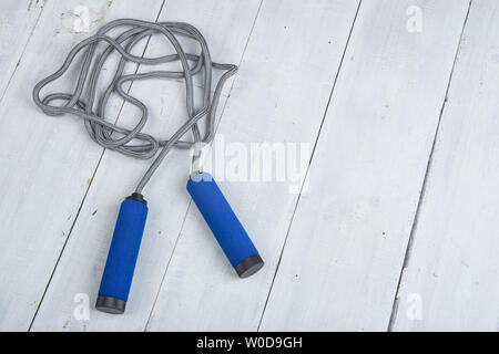 Fitness/sport and healthy lifestyle concept - Jumping/skipping rope with blue handles on white wooden background Stock Photo