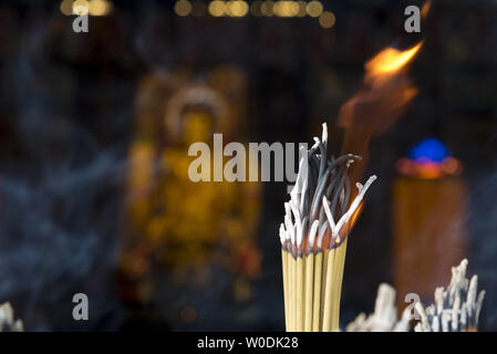 Burning incense sticks with out of focus Buddha statue in the background. Stock Photo