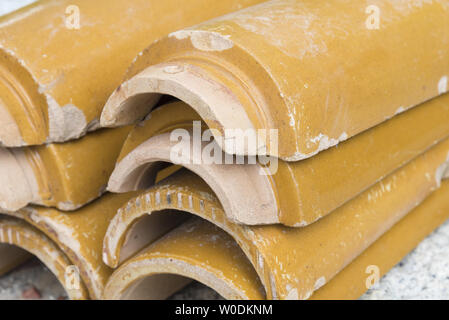 Stacks of yellow ceramic glazed curved roof tiles in a symmetrical pattern. Stock Photo