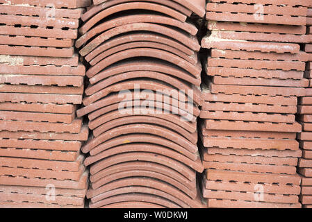 Terracotta roof tiles stacked ready for use with a symmetrical pattern. Stock Photo
