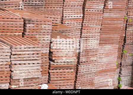 Terracotta roof tiles stacked ready for use with a symmetrical pattern. Stock Photo