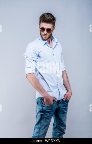 Young man standing in shirt, in profile, hands in pockets, head on the side Stock Photo