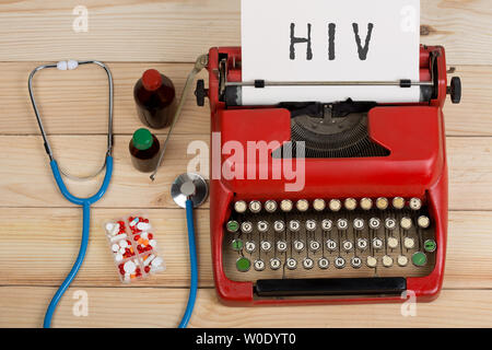 Prescription medicine or medical diagnosis - doctor workplace with blue stethoscope, pills, red typewriter with text HIV on wooden table Stock Photo