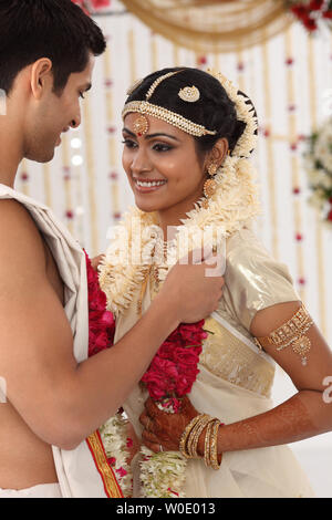 Indian couple performing mala badal ceremony in wedding mandap Stock Photo