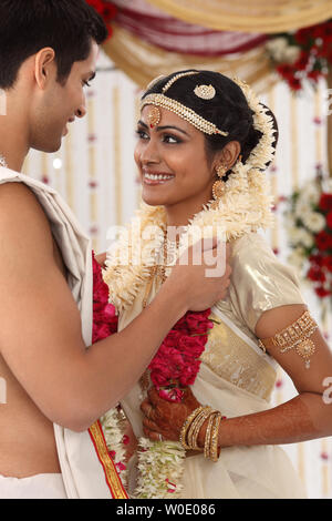 Indian couple performing Mala Badal ceremony in wedding mandap Stock Photo