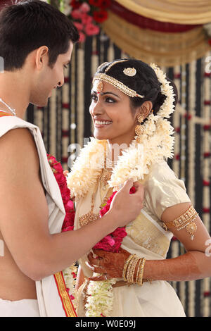 Indian couple performing mala badal ceremony in wedding mandap Stock Photo