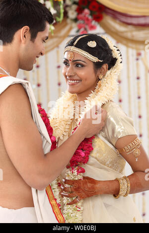 Indian couple performing Mala Badal ceremony in wedding mandap Stock Photo