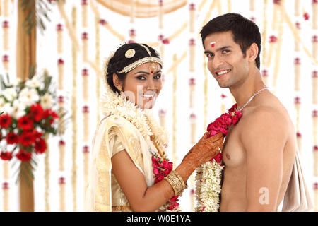 Indian couple performing mala badal ceremony in wedding mandap Stock Photo