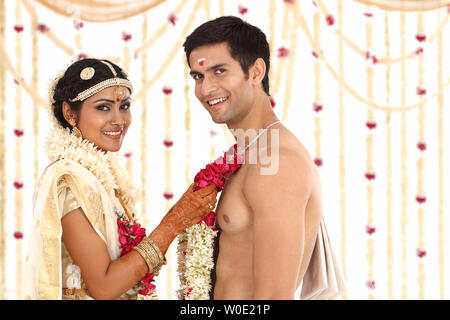 Indian couple performing mala badal ceremony in wedding mandap Stock Photo