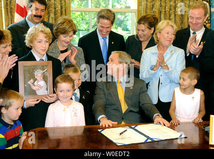 U.S. President George W. Bush looks back to his wife Laura Bush after signing H.R. 1553, the Caroline Pryce Walker Conquer Childhood Cancer Act of 2008, in the Oval Office of the White House in Washington on July 29, 2008. Bush was joined by cancer patient and their  families, members of Congress and his administration and members of the medical field.  (UPI Photo/Kevin Dietsch) Stock Photo