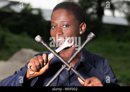 Young smiling mechanic showing her tools in her outdoor studio. Stock Photo