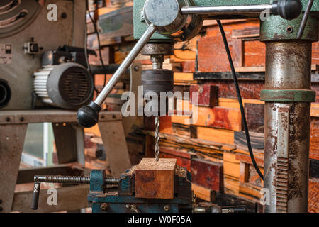 Women standing is craft working drill wood at a work bench with Drill Press power tools at carpenter machine in the workshop Stock Photo