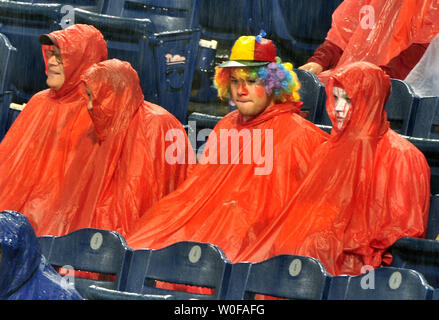 Baseball fans wearing ponchos wait during a rain delay prior to
