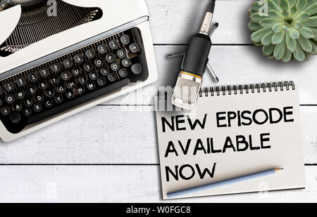 podcast concept, top view of microphone on desk with old typewriter and notepad with text NEW EPISODE AVAILABLE NOW Stock Photo