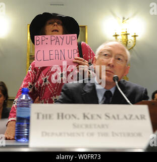 A protester holding a sign reading 'BP: Pay up Clean up' passes by as Secretary of the Interior Ken Salazar testifies before the House Natural Resources Committee regarding the outer continental shelf oil and gas strategy and implications of the Deepwater Horizon rig explosion on Capitol Hill in Washington on May 26, 2010.   UPI/Roger L. Wollenberg Stock Photo